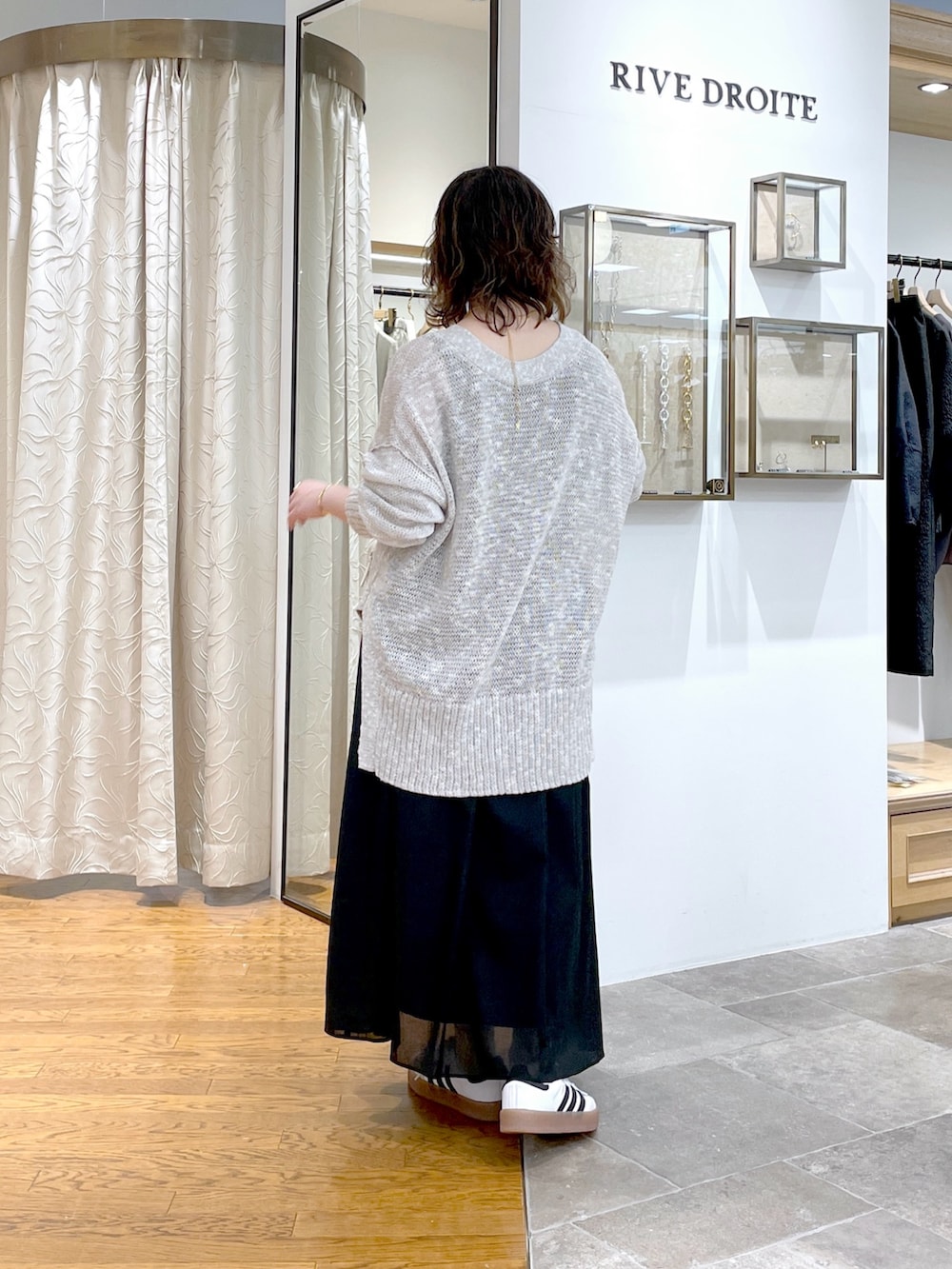 ブラック系のスカート、ホワイト系のボストンバッグ、グレー系のカーディガン/ボレロを着用したレディースの春コーディネートの4枚目の写真