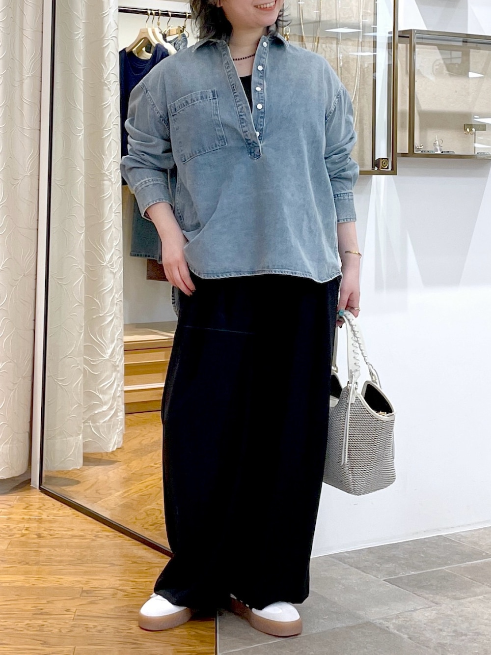 ブルー系のシャツ/ブラウス、ホワイト系のハンドバッグ、ブラック系のスラックスを着用したレディースの春コーディネートの4枚目の写真