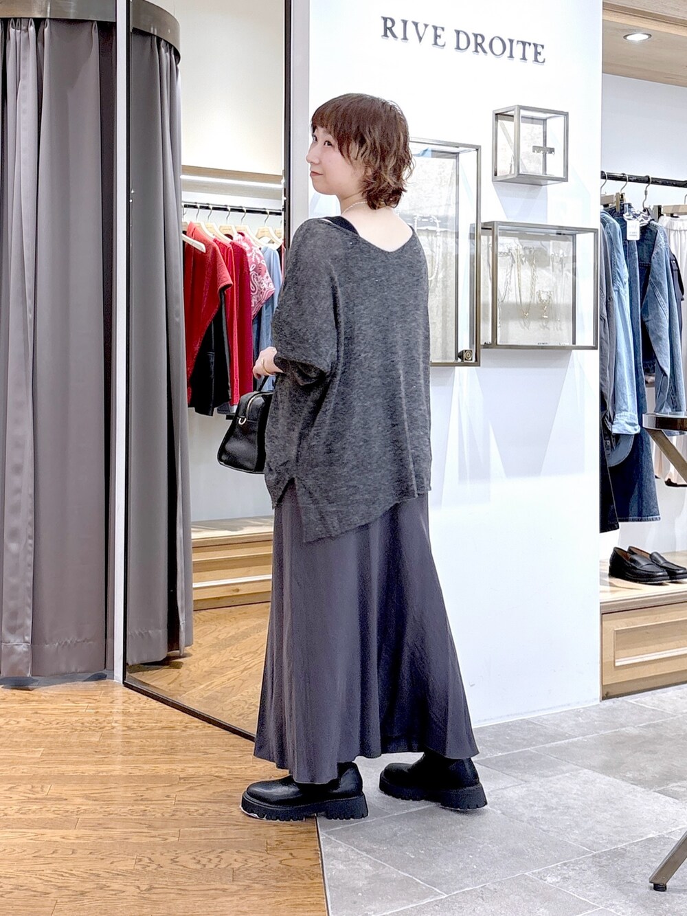 ブラック系のタンクトップ、グレー系のニット/セーター、ブラック系のボストンバッグを着用したレディースの秋コーディネートの2枚目の写真