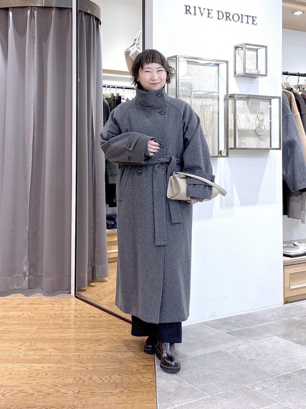 グレー系のニット/セーター、ベージュ系のハンドバッグ、グレー系のその他アウターを着用したレディースの秋コーディネートの2枚目の写真