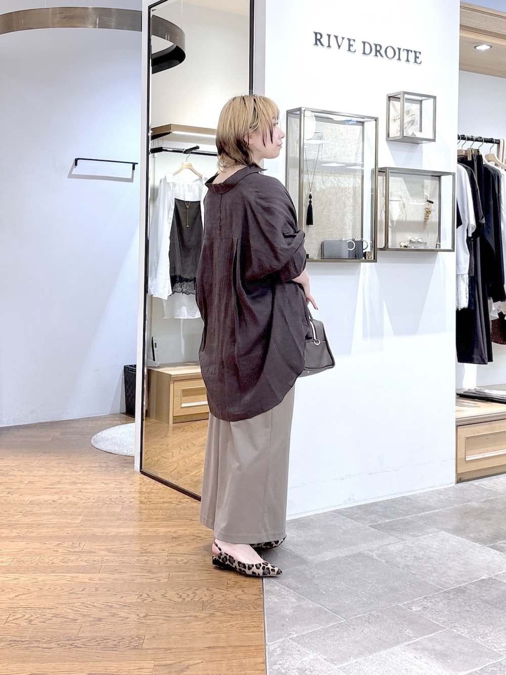 ブラック系のニット/セーター、ブラウン系のシャツ/ブラウス、ブラウン系のボストンバッグを着用したレディースの夏コーディネートの3枚目の写真