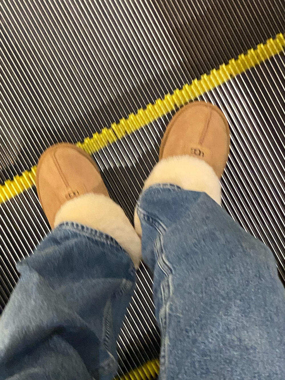 ブラウン系のスリッポン、ブラック系のショルダーバッグ、ブルー系のデニムパンツを着用したレディースの秋コーディネートの2枚目の写真