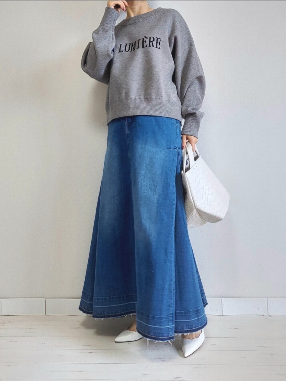 グレー系のニット/セーター、ブルー系のデニムスカートを着用したレディースの冬コーディネートの2枚目の写真
