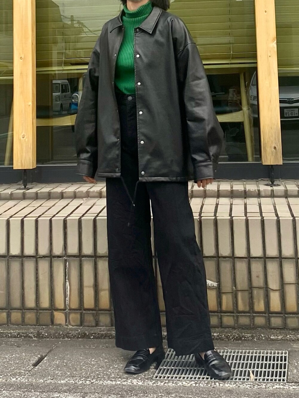 ブラック系のデニムパンツ、ブラック系のその他アウター、グリーン系のTシャツ/カットソーを着用したレディースの秋コーディネートの2枚目の写真