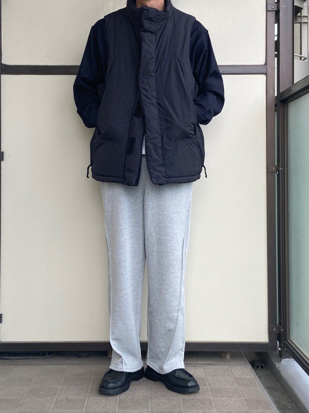 グレー系のスウェットパンツ、ブラック系のダウンベスト、ブラック系のドレスシューズを着用したメンズの秋コーディネートの3枚目の写真