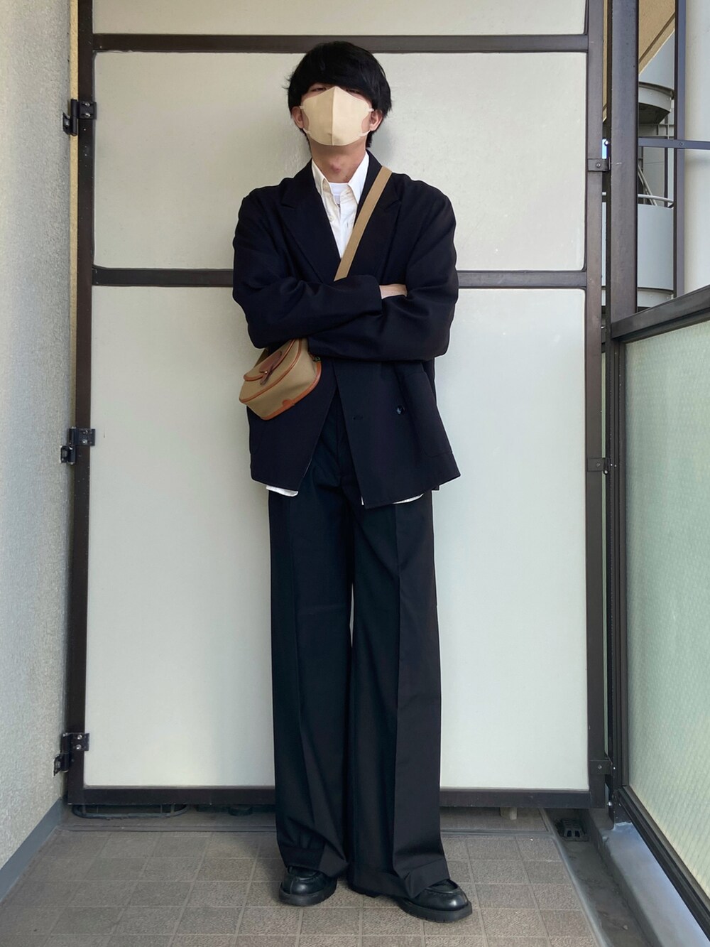 ブラック系のスラックス、ブラック系のドレスシューズ、グリーン系のショルダーバッグを着用したメンズの冬コーディネートの3枚目の写真