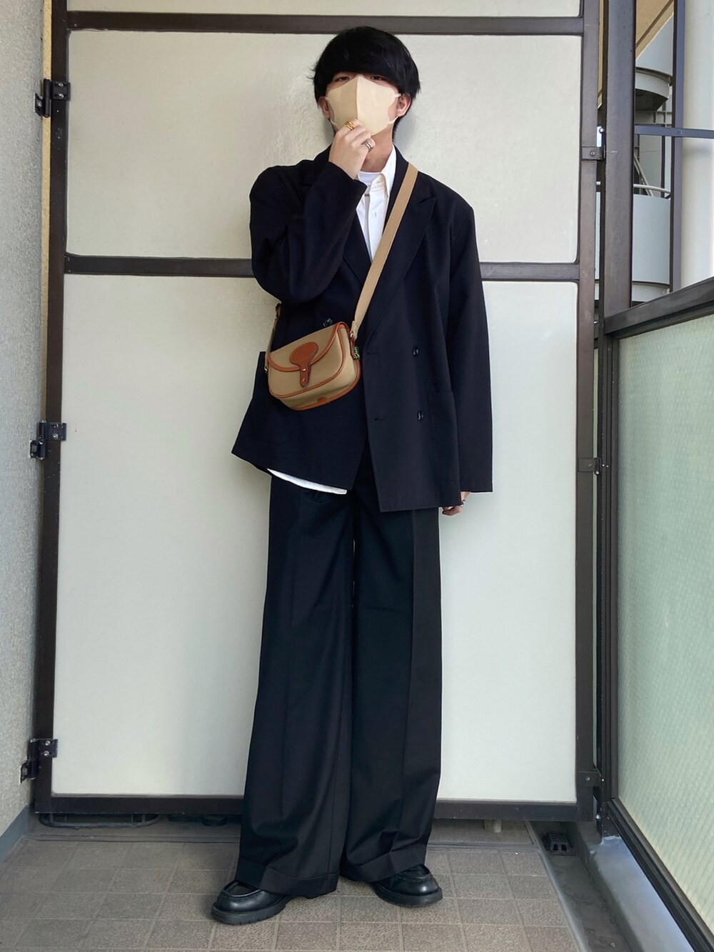 ブラック系のスラックス、ブラック系のドレスシューズ、グリーン系のショルダーバッグを着用したメンズの冬コーディネートの2枚目の写真