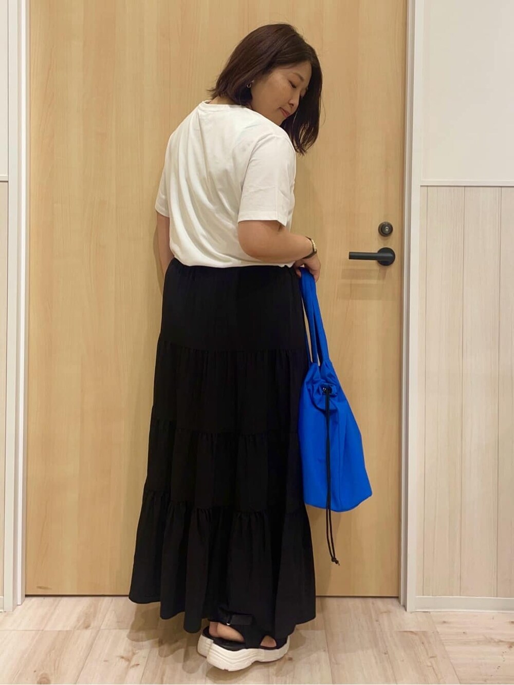 ホワイト系のTシャツ/カットソー、ブラック系のスカート、ブラック系のサンダルを着用したレディースの夏コーディネートの3枚目の写真