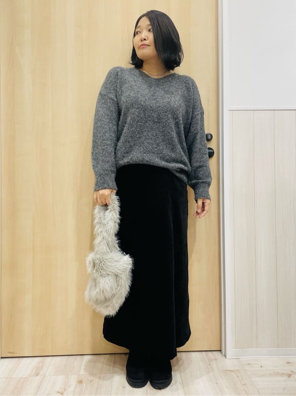 ホワイト系のブルゾン、グレー系のニット/セーター、ブラック系のスカートを着用したレディースの秋コーディネートの4枚目の写真