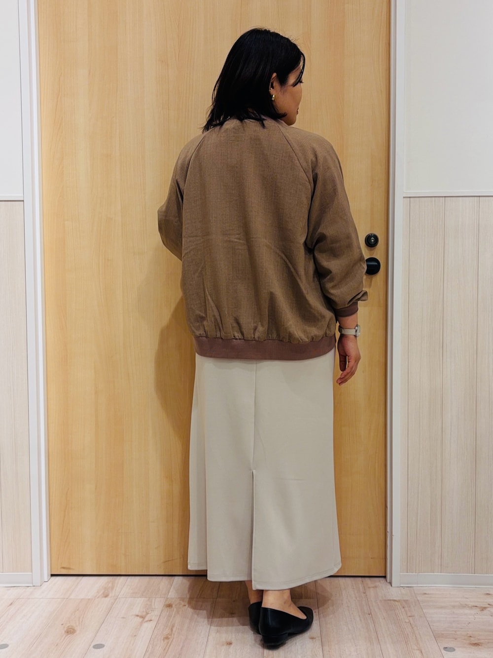 ベージュ系のスカート、ブラック系のパンプス、イエロー系のブルゾンを着用したレディースの春コーディネートの3枚目の写真