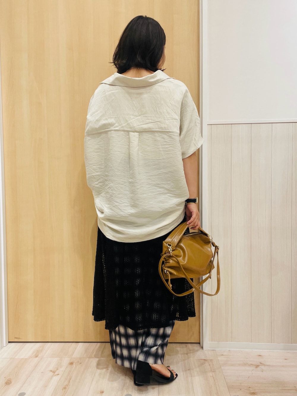 ベージュ系のシャツ/ブラウス、ホワイト系のタンクトップ、ブラック系のスカートを着用したレディースの秋コーディネートの3枚目の写真