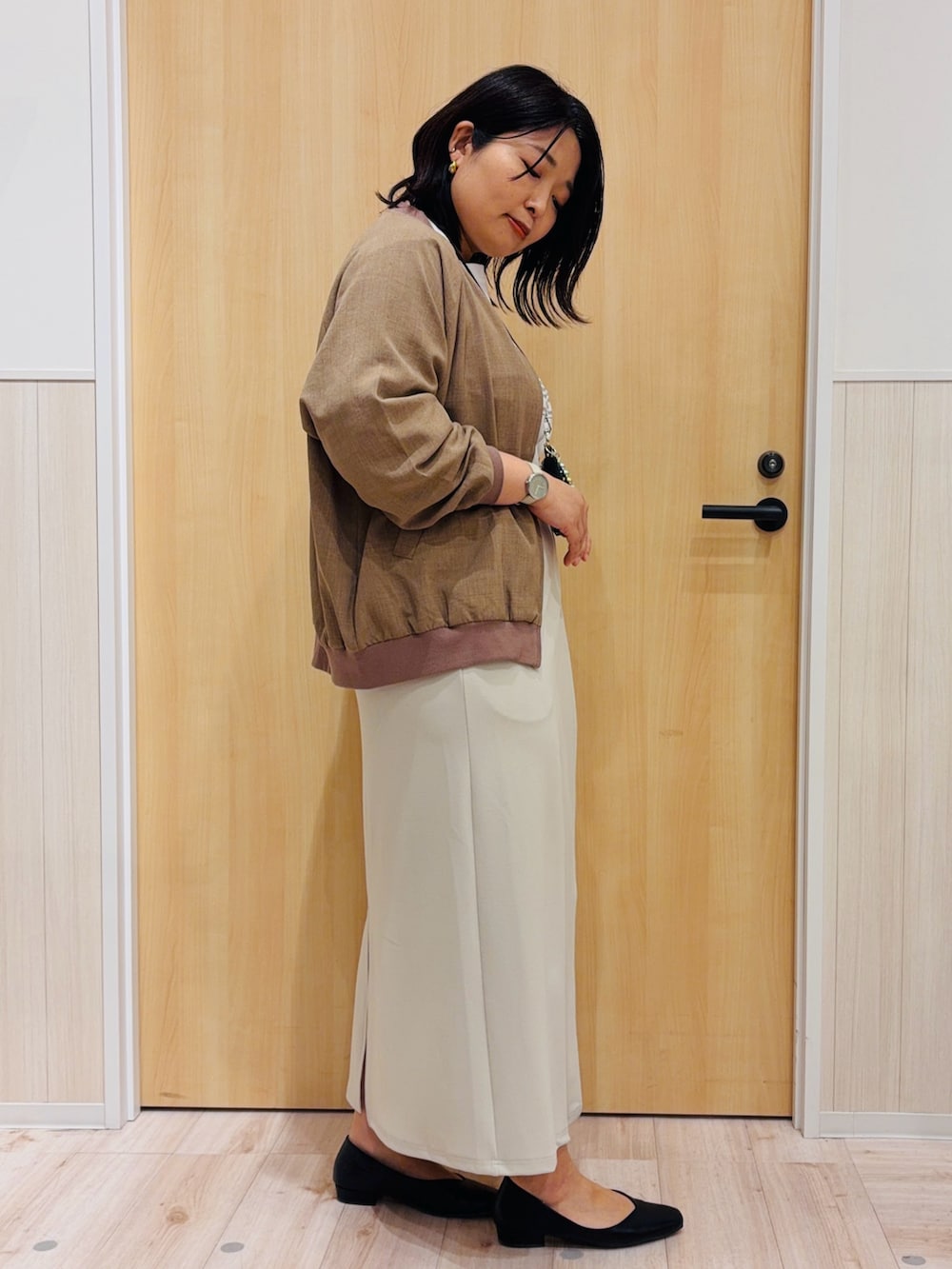 ベージュ系のスカート、ブラック系のパンプス、イエロー系のブルゾンを着用したレディースの春コーディネートの2枚目の写真