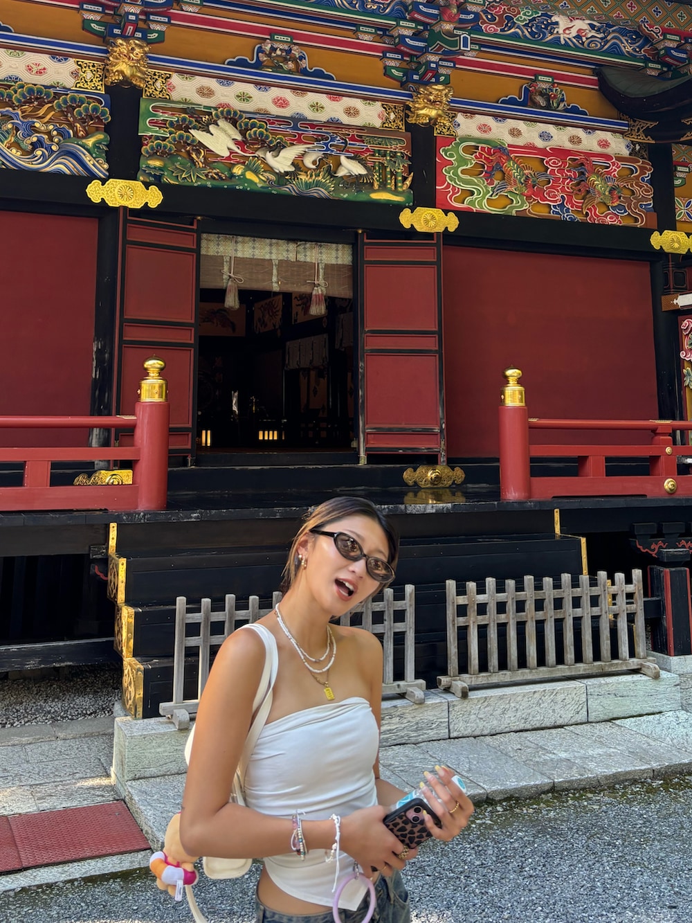 ホワイト系のチューブトップ、ホワイト系のショルダーバッグ、ブルー系のデニムパンツを着用したレディースの秋コーディネートの4枚目の写真