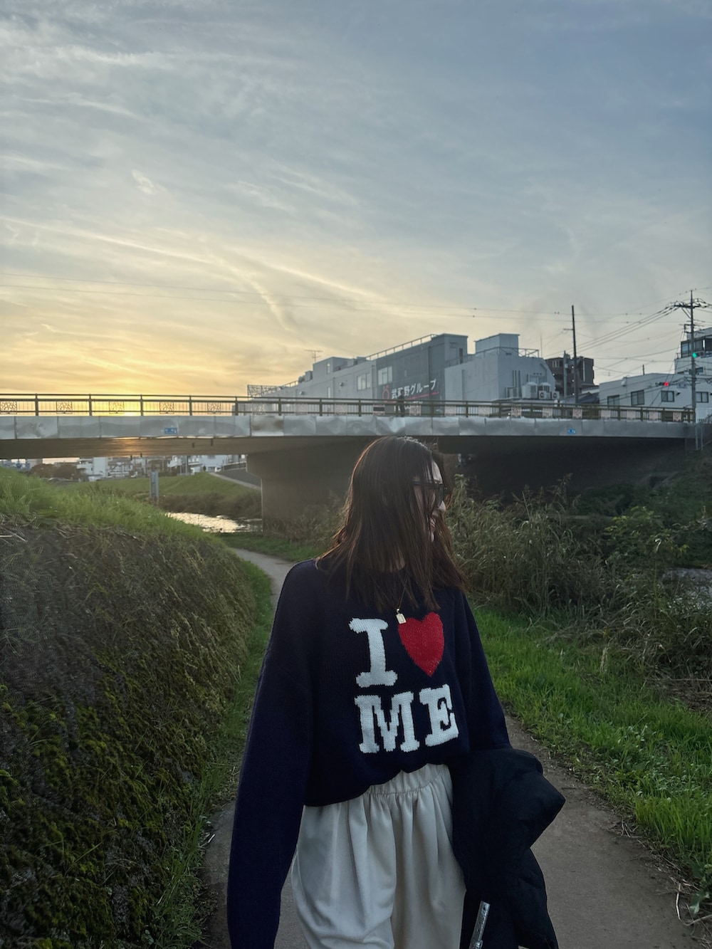 ブルー系のニット/セーター、ブラウン系のブーツ、ブラック系のダウンベストを着用したレディースの秋コーディネートの2枚目の写真