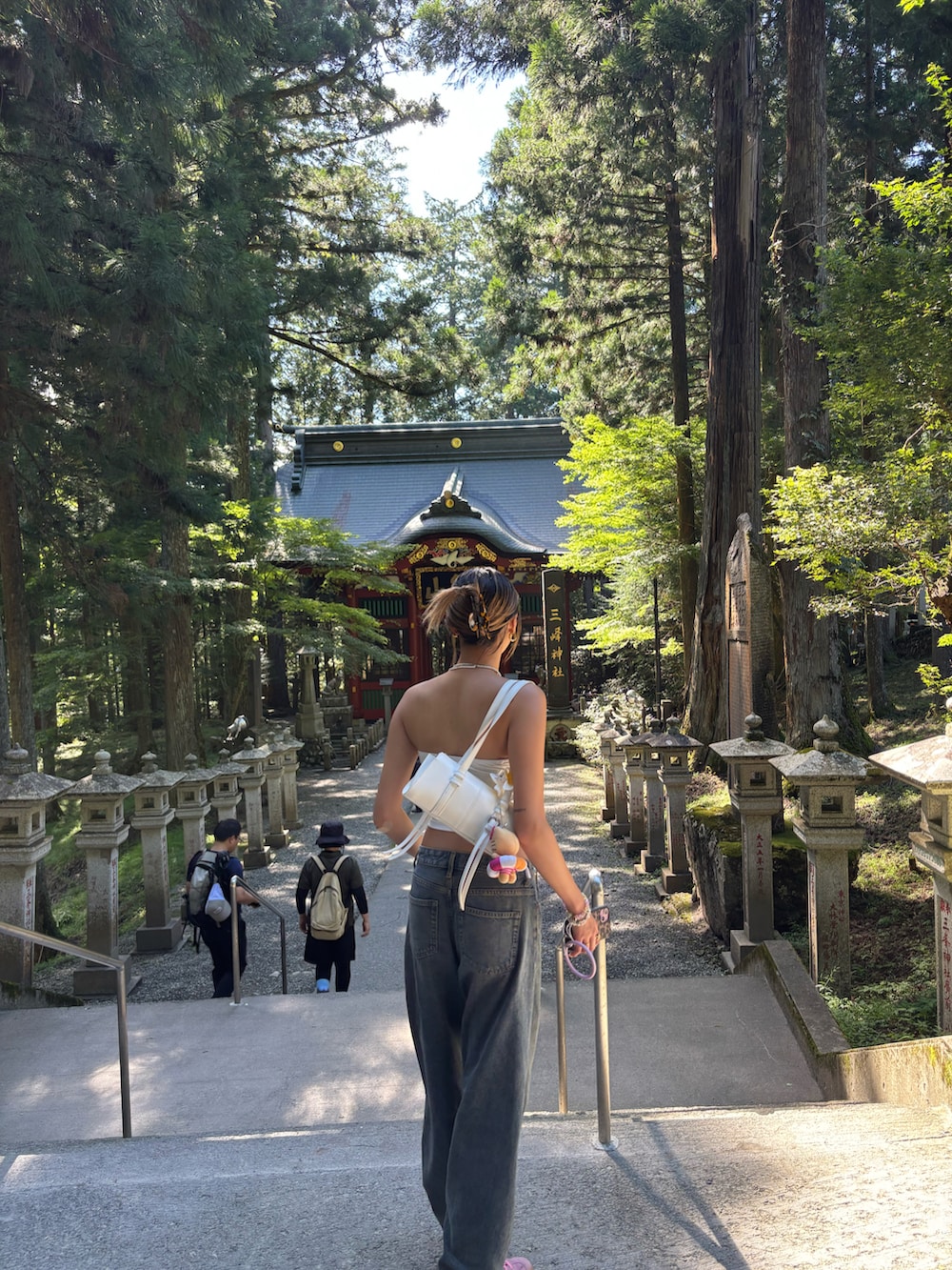 ホワイト系のチューブトップ、ホワイト系のショルダーバッグ、ブルー系のデニムパンツを着用したレディースの秋コーディネートの3枚目の写真