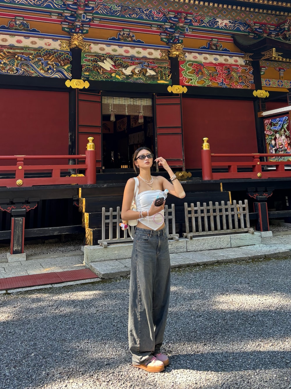 ホワイト系のチューブトップ、ホワイト系のショルダーバッグ、ブルー系のデニムパンツを着用したレディースの秋コーディネートの5枚目の写真