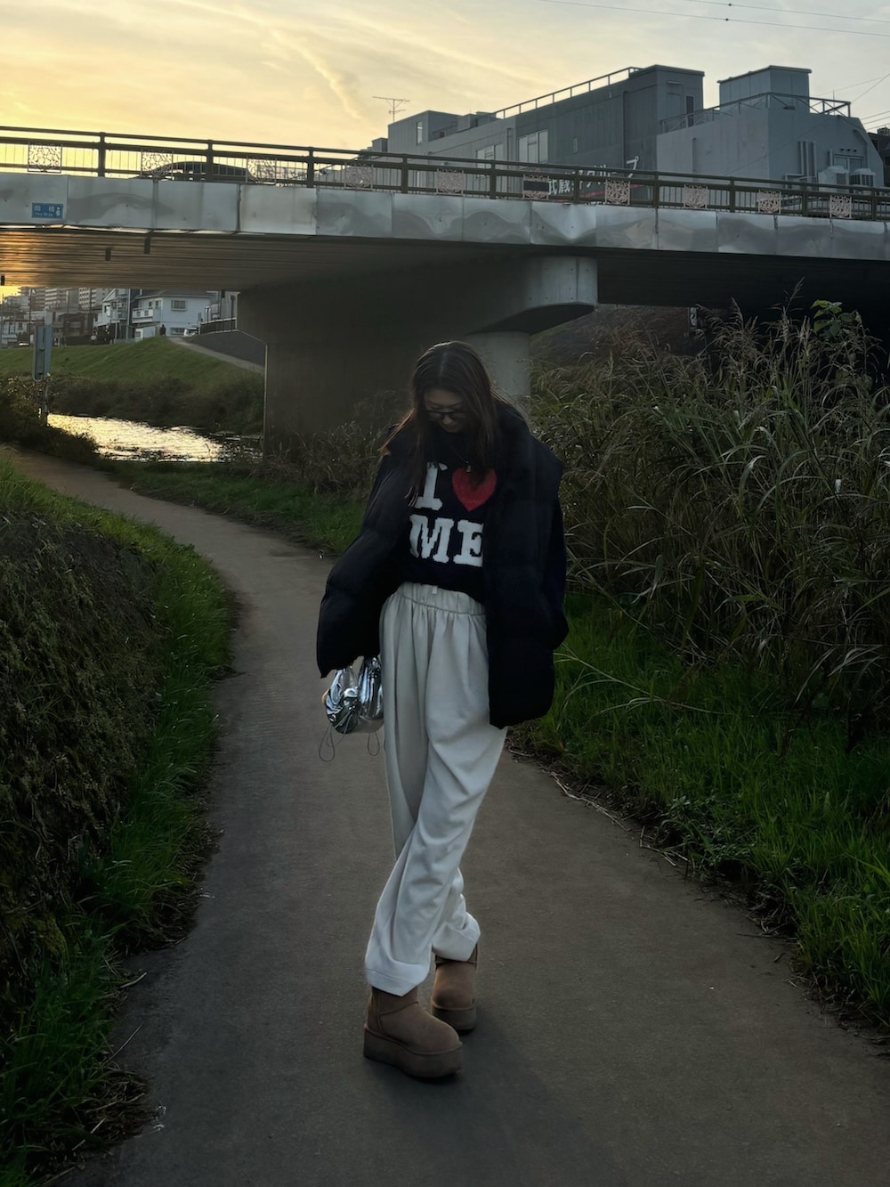 ブルー系のニット/セーター、ブラウン系のブーツ、ブラック系のダウンベストを着用したレディースの秋コーディネートの4枚目の写真