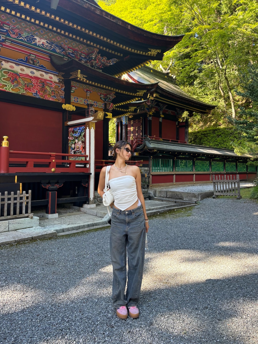 ホワイト系のチューブトップ、ホワイト系のショルダーバッグ、ブルー系のデニムパンツを着用したレディースの秋コーディネートの2枚目の写真