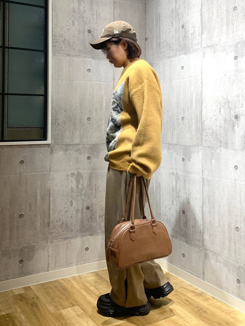 ブラック系のブーツ、イエロー系のボストンバッグ、イエロー系のニット/セーターを着用したレディースの秋コーディネートの5枚目の写真