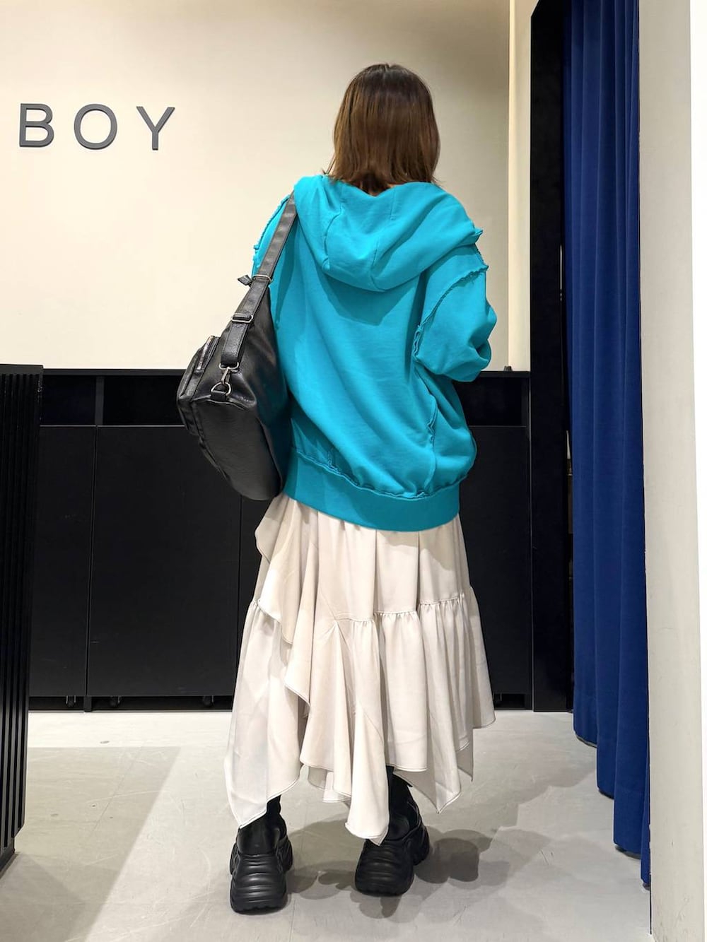 ブラック系のブーツ、ベージュ系のスカート、ホワイト系のニット/セーターを着用したレディースの冬コーディネートの4枚目の写真