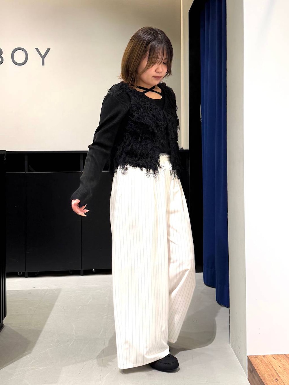 ブラック系のハンドバッグ、ブラック系のニット/セーター、ホワイト系のスラックスを着用したレディースの冬コーディネートの3枚目の写真