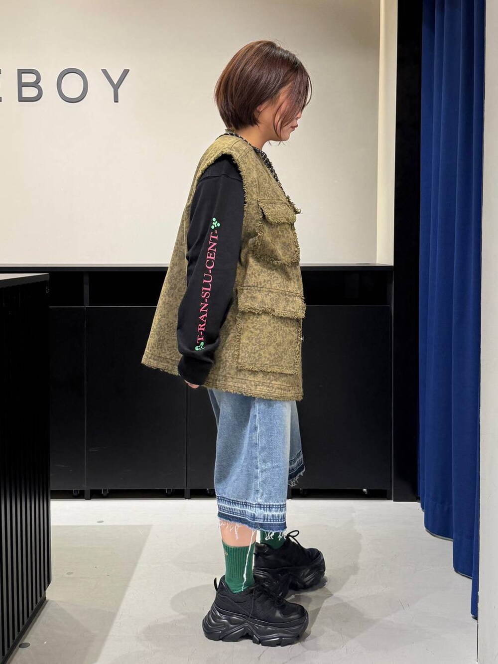 ブラック系のスニーカー、ブラック系のショルダーバッグ、ブルー系のデニムパンツを着用したレディースの夏コーディネートの4枚目の写真