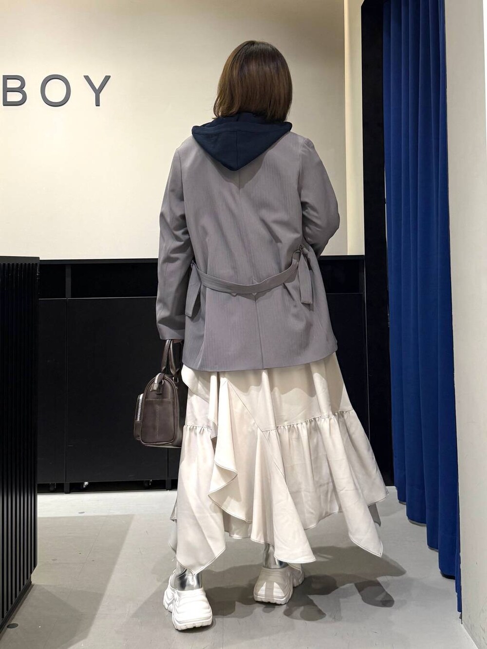 ホワイト系のブーツ、グレー系のテーラードジャケット、ベージュ系のスカートを着用したレディースの冬コーディネートの5枚目の写真