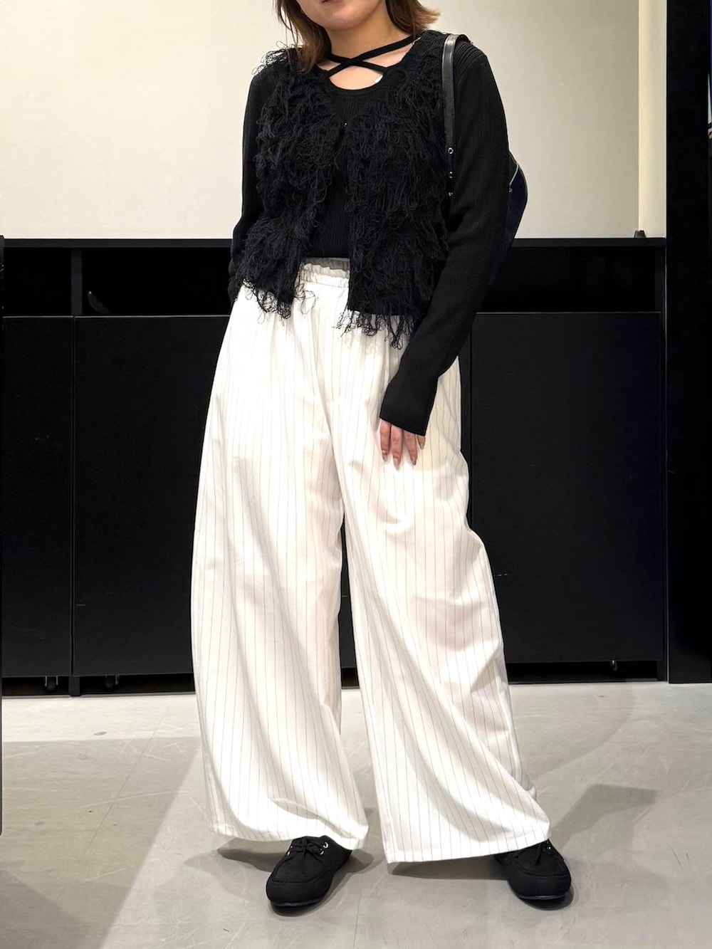 ブラック系のハンドバッグ、ブラック系のニット/セーター、ホワイト系のスラックスを着用したレディースの冬コーディネートの2枚目の写真