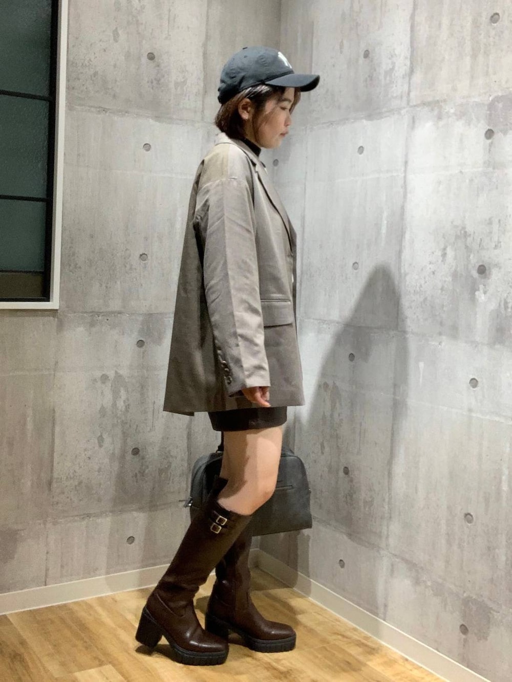 グレー系のボストンバッグ、ブラウン系のテーラードジャケット、ホワイト系のニット/セーターを着用したレディースの秋コーディネートの3枚目の写真