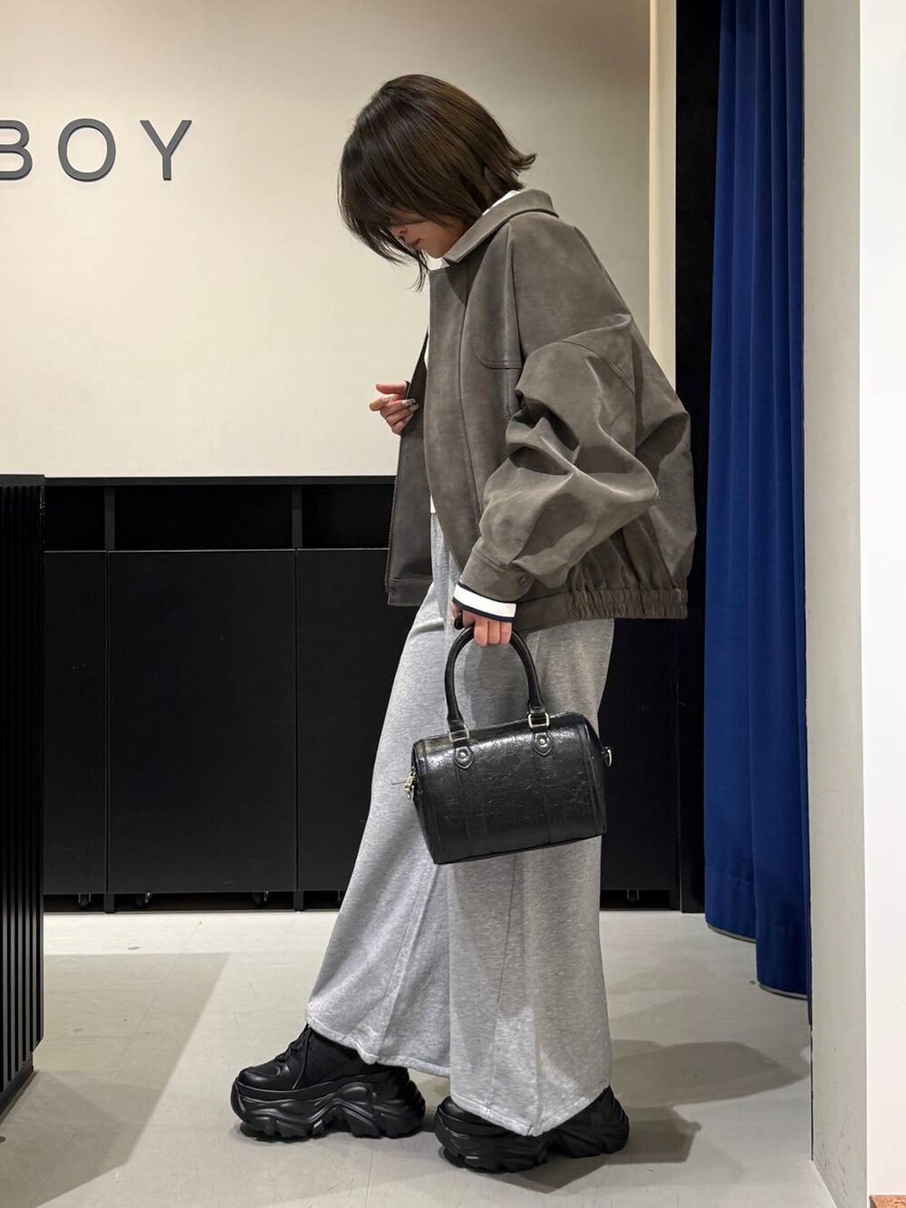 ブラック系のスニーカー、ブラック系のボストンバッグ、ホワイト系のニット/セーターを着用したレディースの冬コーディネートの6枚目の写真