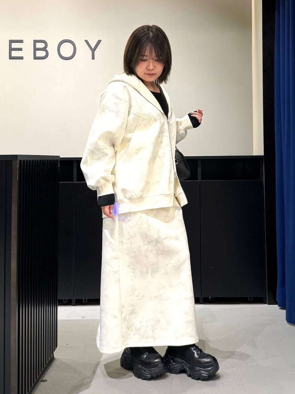 ブラック系のブーツ、ホワイト系のスカート、ホワイト系のパーカーを着用したレディースの冬コーディネートの3枚目の写真