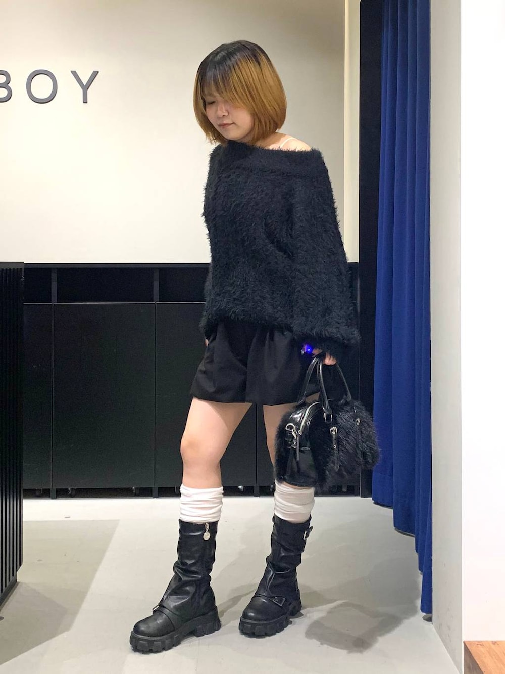 ホワイト系のキャミソール、ブラック系のワンピース、ブラック系のボストンバッグを着用したレディースの冬コーディネートの7枚目の写真