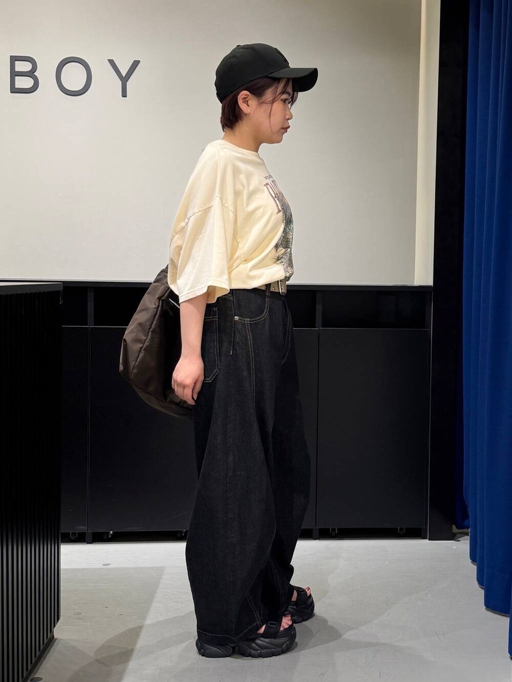 ブラック系のサンダル、ベージュ系のTシャツ/カットソー、ブラック系のデニムパンツを着用したレディースの夏コーディネートの3枚目の写真