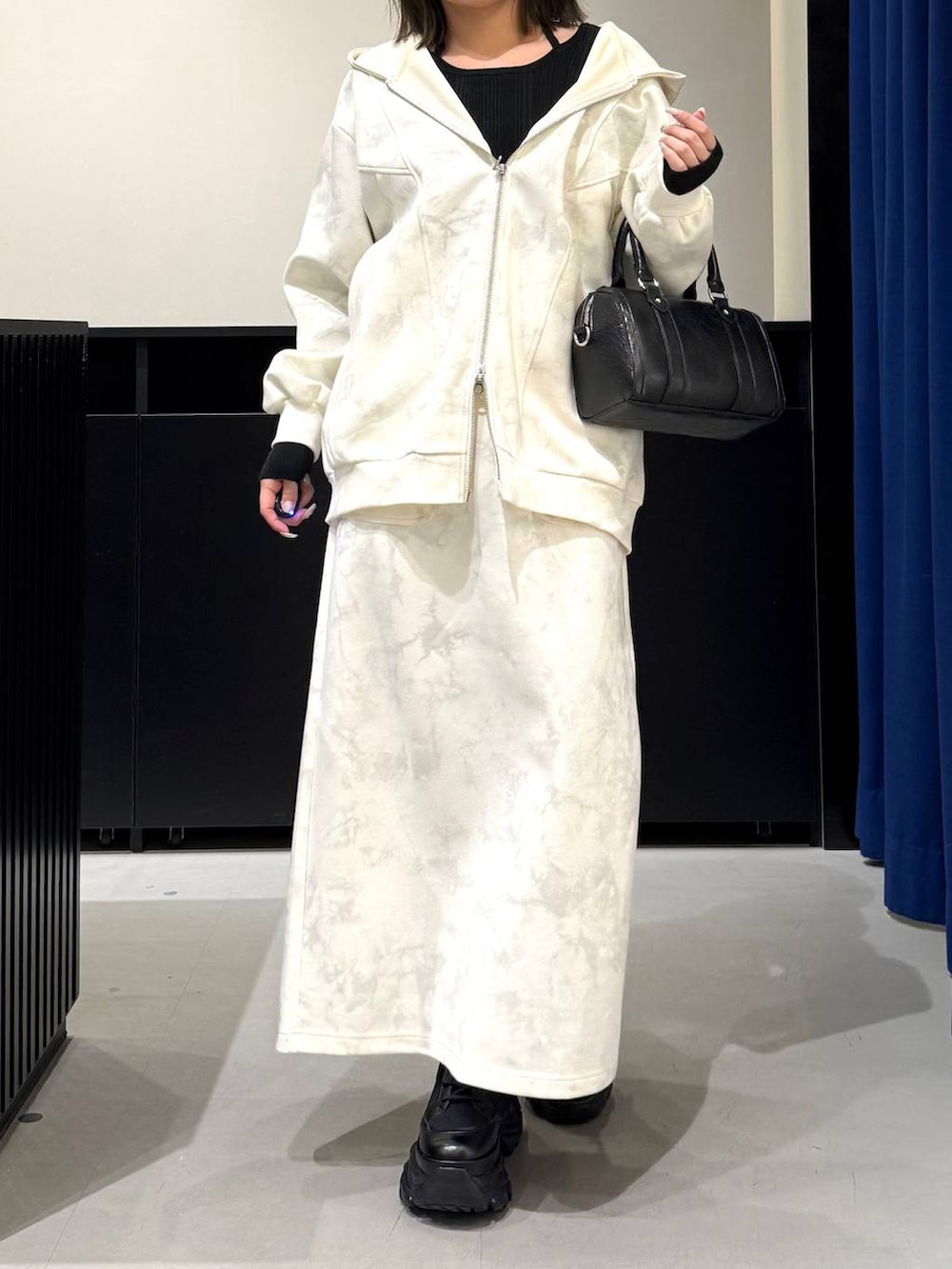 ブラック系のブーツ、ホワイト系のスカート、ホワイト系のパーカーを着用したレディースの冬コーディネートの2枚目の写真