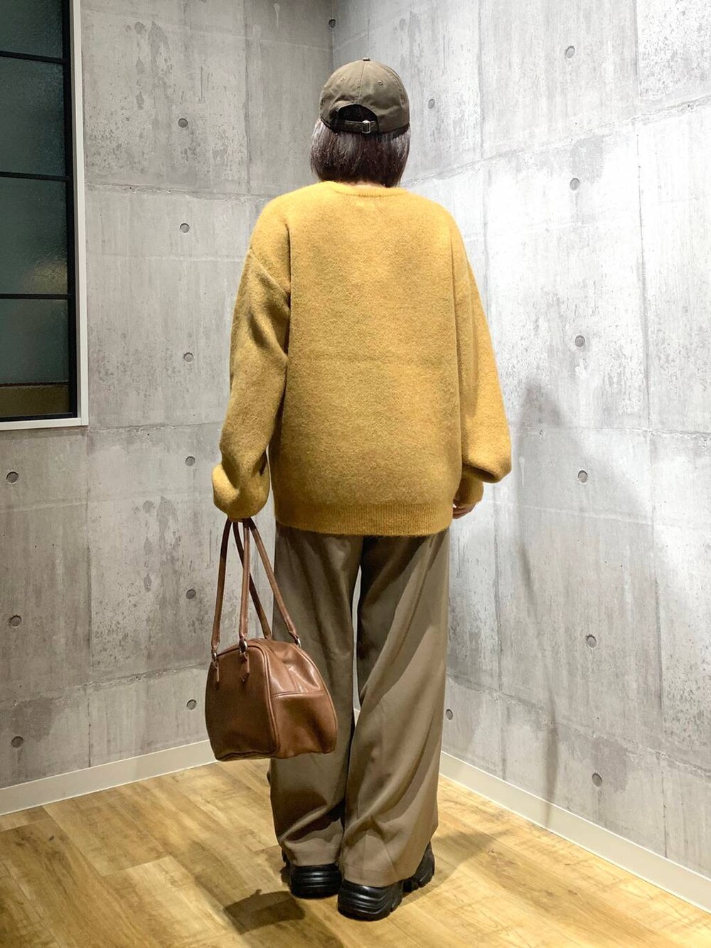 ブラック系のブーツ、イエロー系のボストンバッグ、イエロー系のニット/セーターを着用したレディースの秋コーディネートの4枚目の写真