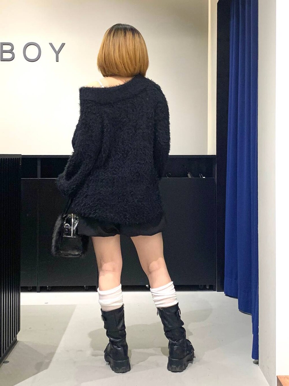 ホワイト系のキャミソール、ブラック系のワンピース、ブラック系のボストンバッグを着用したレディースの冬コーディネートの5枚目の写真