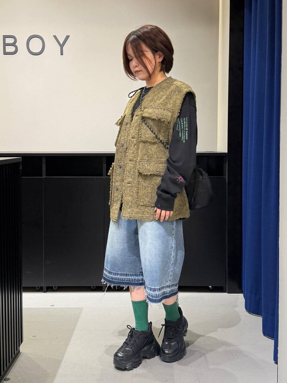 ブラック系のスニーカー、ブラック系のショルダーバッグ、ブルー系のデニムパンツを着用したレディースの夏コーディネートの6枚目の写真