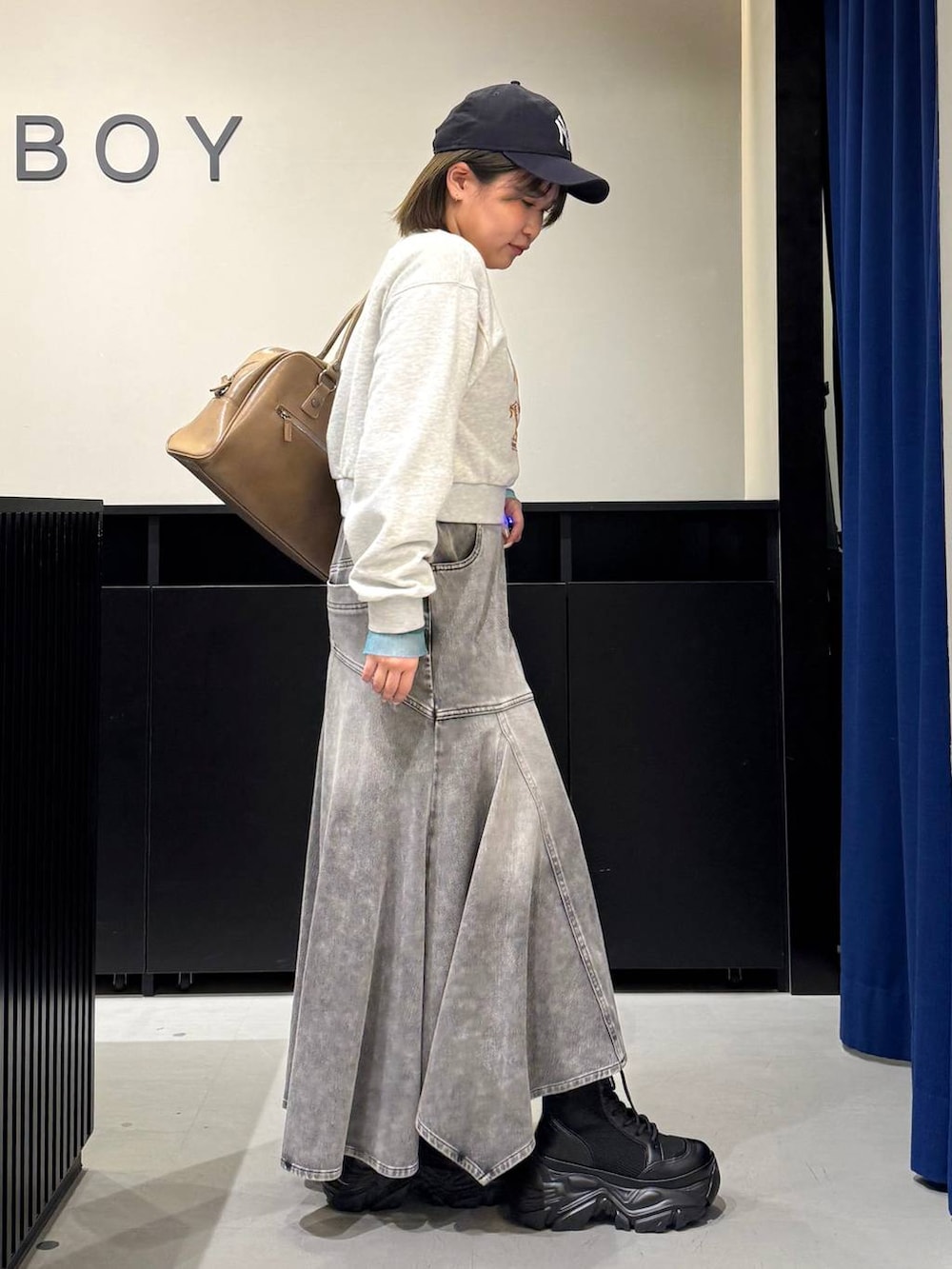 ブラック系のブーツ、イエロー系のボストンバッグ、グレー系のスウェットを着用したレディースの冬コーディネートの4枚目の写真