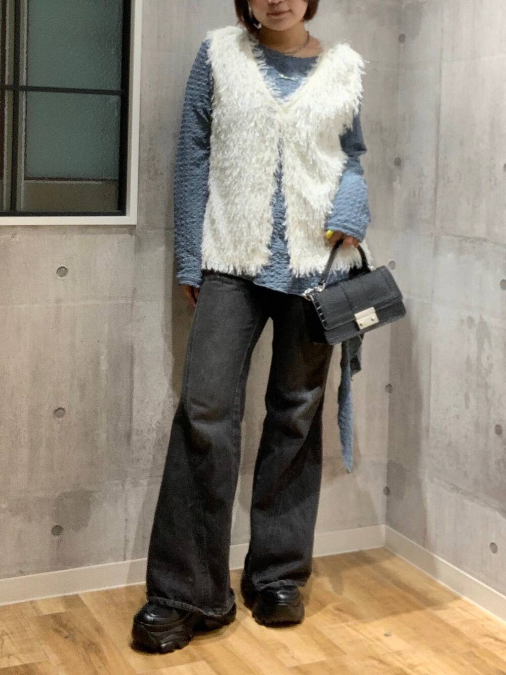 ブラック系のスニーカー、ブラック系のデニムパンツ、ホワイト系のベストを着用したレディースの秋コーディネートの2枚目の写真