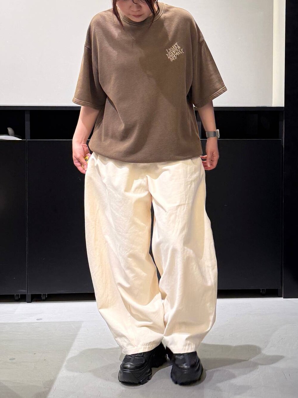 ブラック系のスニーカー、ベージュ系のその他パンツ、ブラウン系のTシャツ/カットソーを着用したレディースの夏コーディネートの2枚目の写真