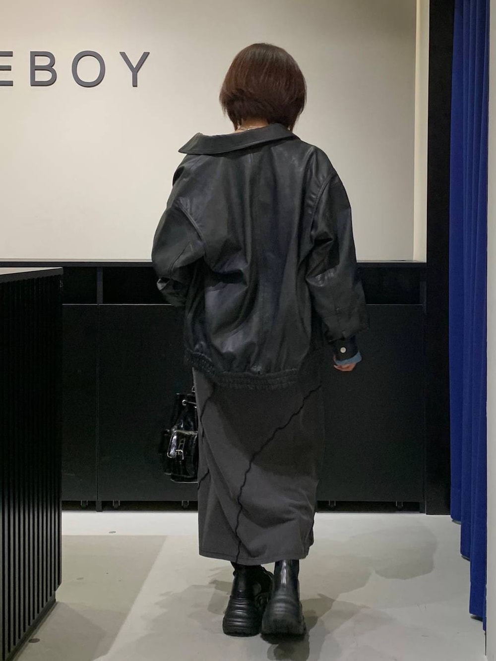 ブラック系のブーツ、ブラック系のショルダーバッグ、ブラック系のワンピースを着用したレディースの秋コーディネートの5枚目の写真