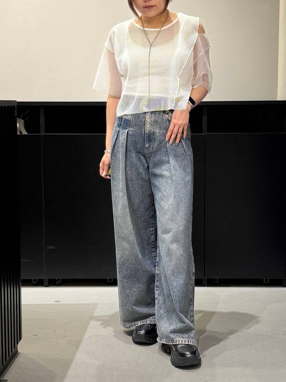 ブルー系のデニムパンツ、ブラック系のスニーカー、ホワイト系のTシャツ/カットソーを着用したレディースの夏コーディネートの2枚目の写真