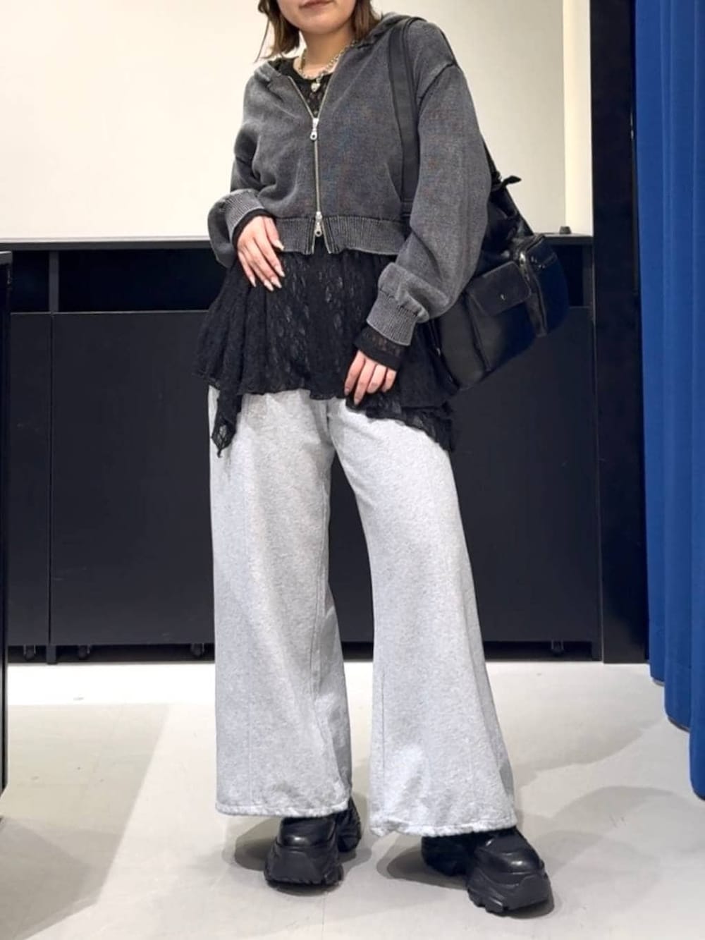 ブラック系のブーツ、グレー系のパーカー、ブラック系のチュニックを着用したレディースの冬コーディネートの2枚目の写真