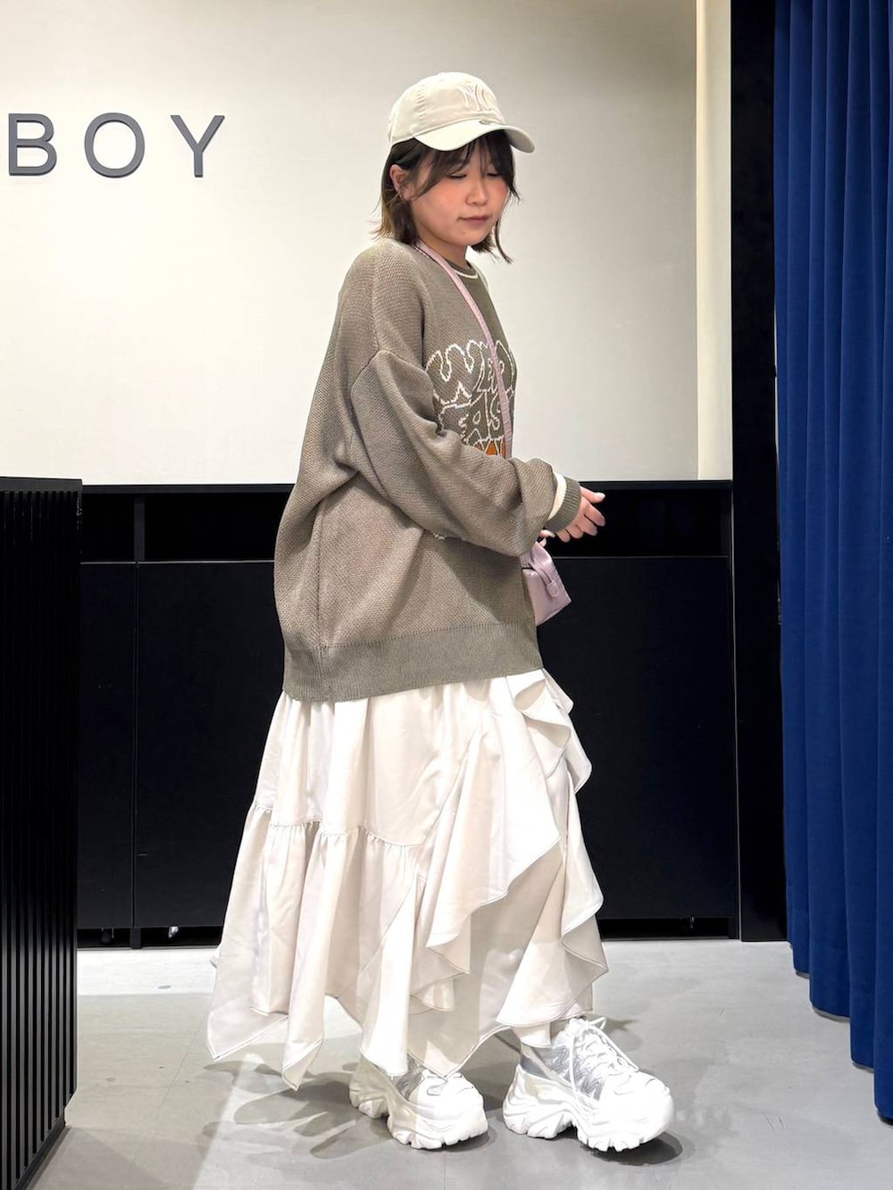 ホワイト系のスニーカー、ベージュ系のスカート、ピンク系のハンドバッグを着用したレディースの冬コーディネートの3枚目の写真