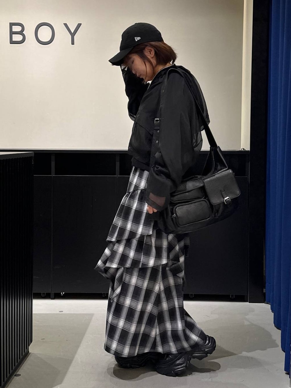 ブラック系のスニーカー、ブラック系のショルダーバッグ、ホワイト系のスカートを着用したレディースの秋コーディネートの6枚目の写真