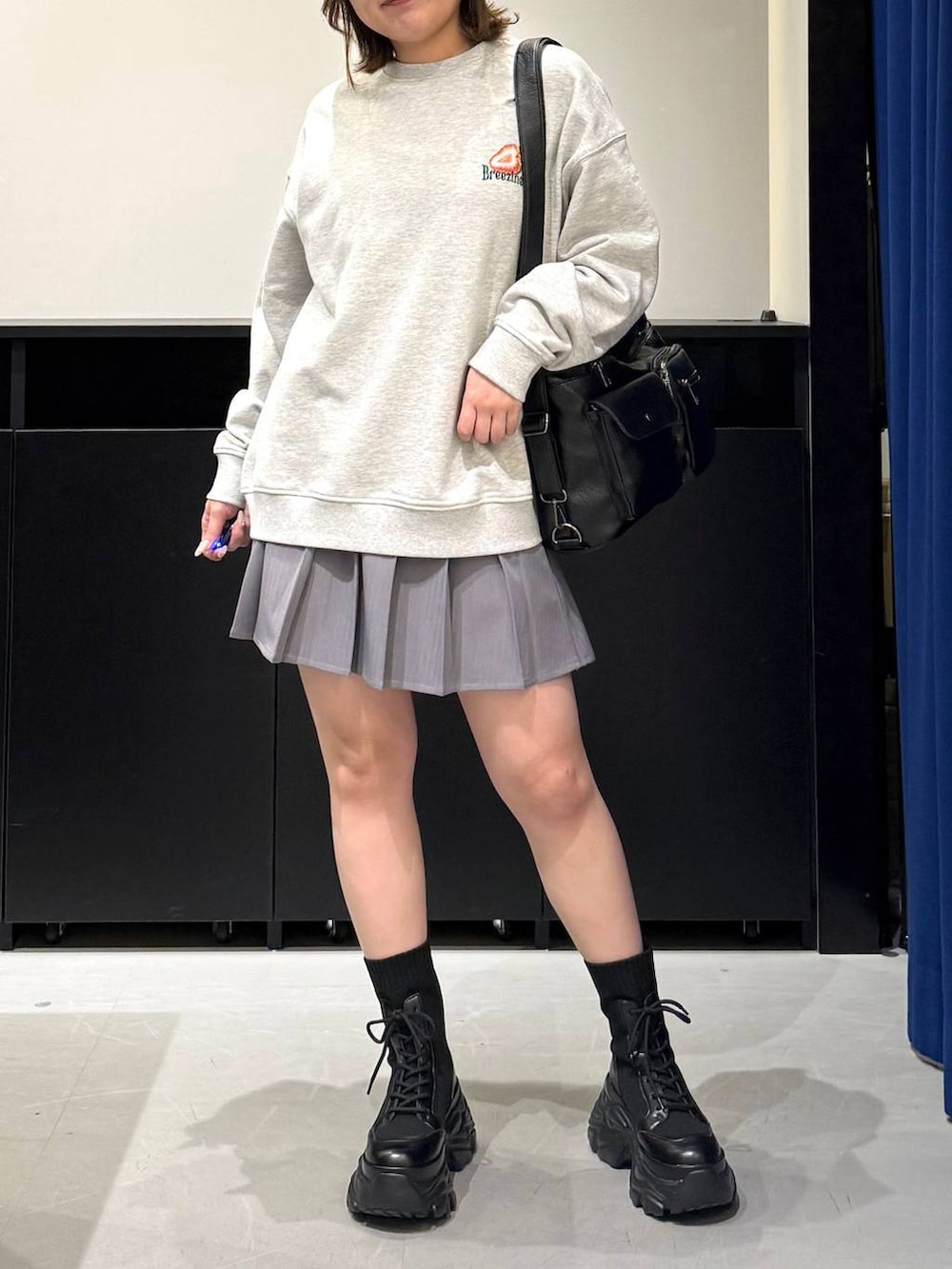 ブラック系のブーツ、グレー系のスウェット、ブラック系のショルダーバッグを着用したレディースの冬コーディネートの2枚目の写真