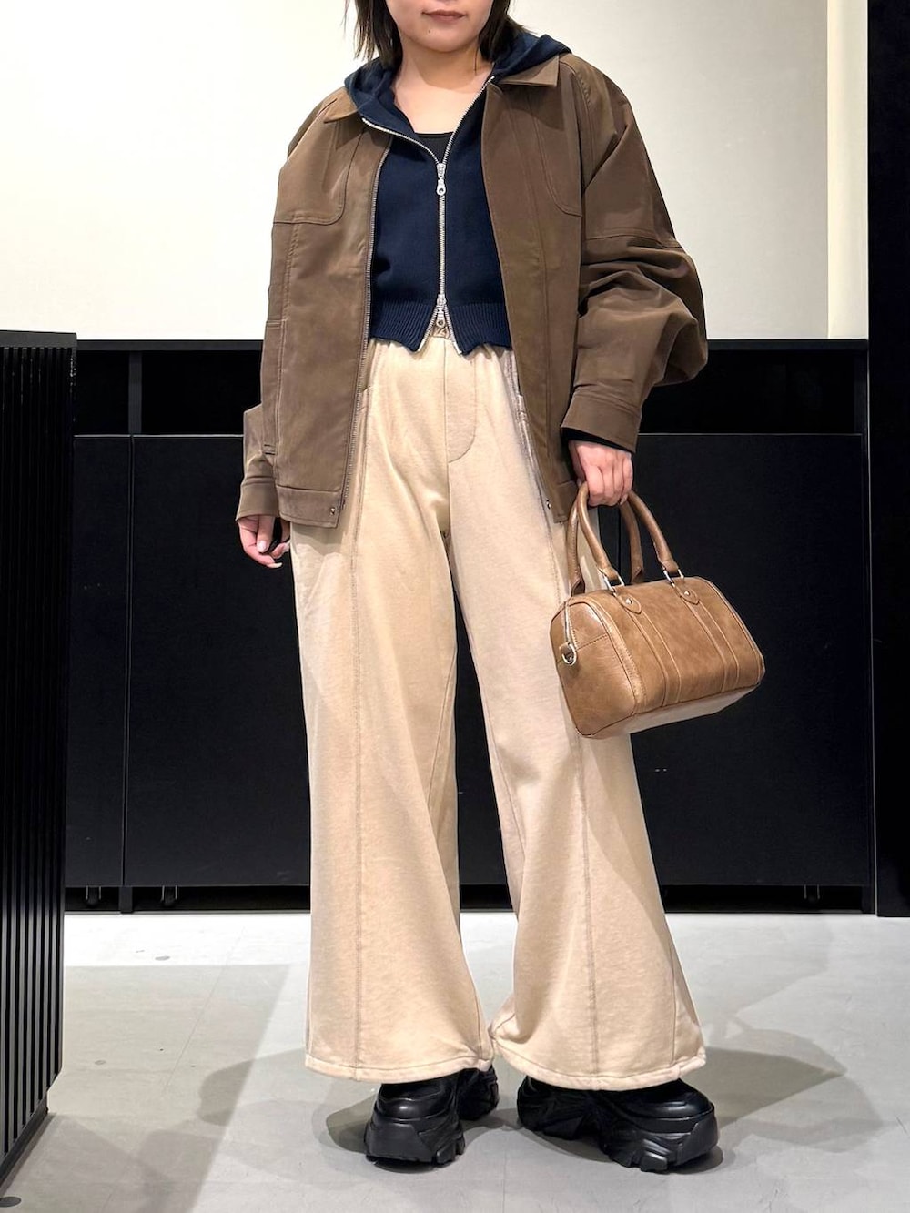 ブラック系のスニーカー、ブラウン系のボストンバッグ、ブルー系のパーカーを着用したレディースの冬コーディネートの2枚目の写真