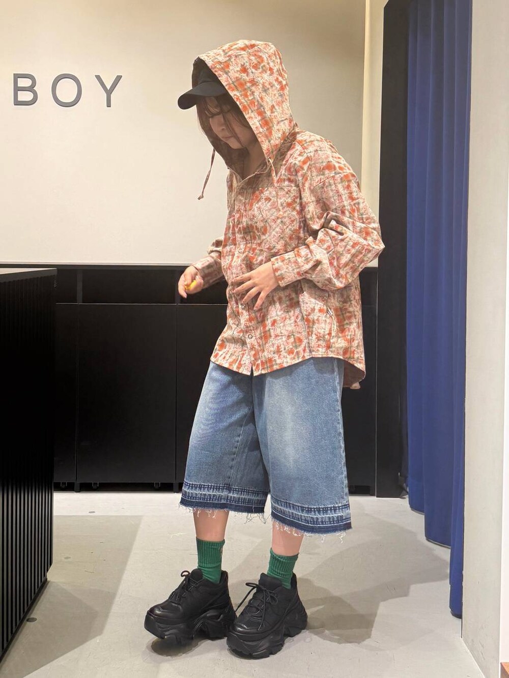 ブラック系のスニーカー、ブルー系のデニムパンツ、オレンジ系のシャツ/ブラウスを着用したレディースの夏コーディネートの7枚目の写真