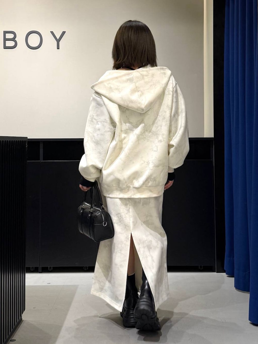 ブラック系のブーツ、ホワイト系のスカート、ホワイト系のパーカーを着用したレディースの冬コーディネートの5枚目の写真