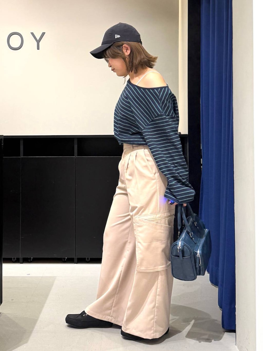 ホワイト系のキャミソール、ブルー系のショルダーバッグ、ベージュ系のスラックスを着用したレディースの冬コーディネートの5枚目の写真